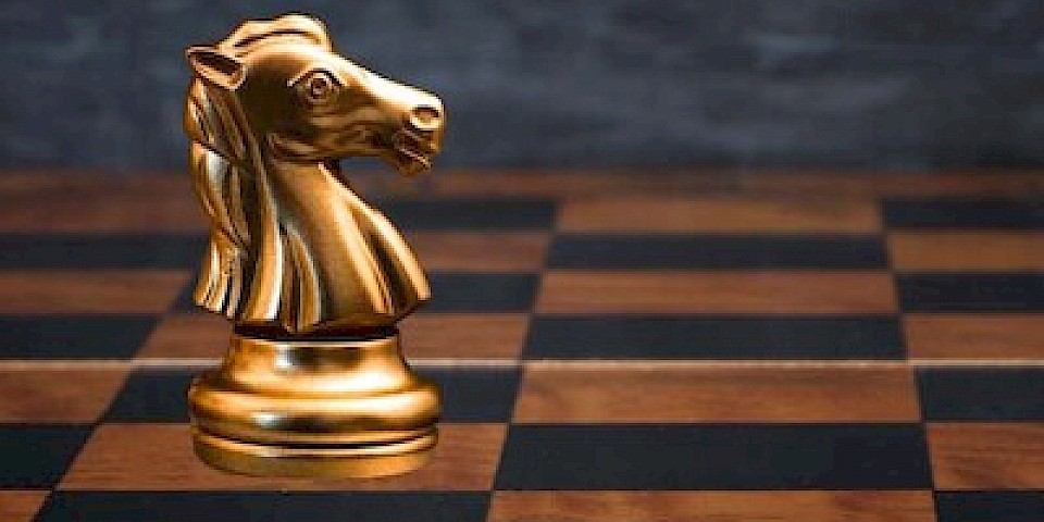 Chessboard with black and white horses, a golden horse in the centre.