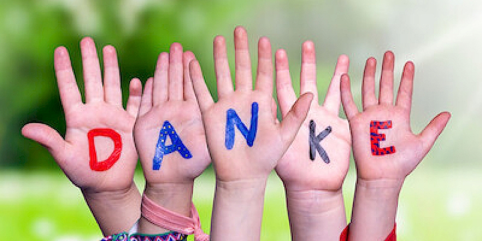 Viele Hände zeigen nach oben, die Handflächen mit Buchstaben bemalt bilde sie zusammen die Worte: Danke Euch allen.