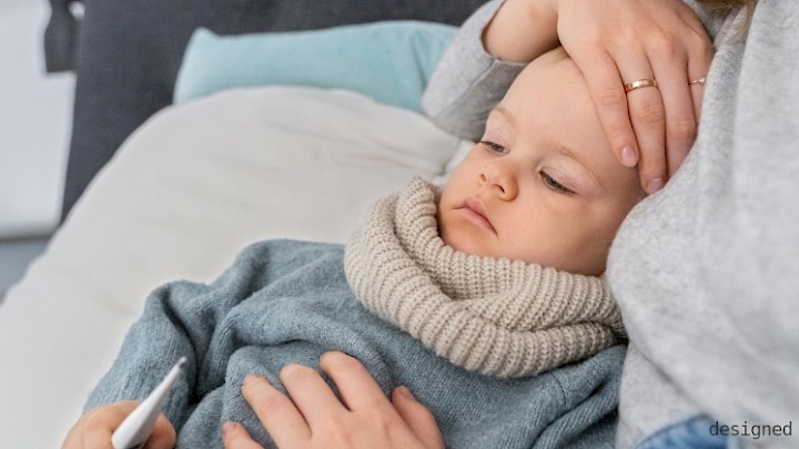 A mother lovingly holds her feverish toddler in her arms. A moment full of care, closeness and security.